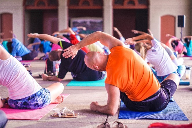 A yoga class full of people stretching, arms over their heads.