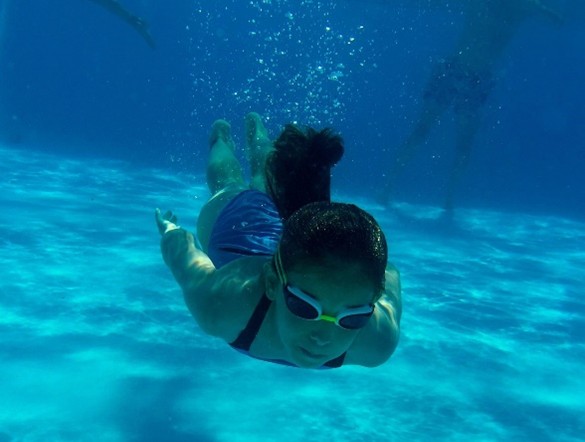 A girl swimming underwater in a swimming pool.